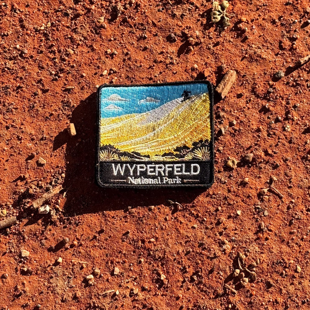 Wyperfeld National Park embroidered travel patch with a sandboarder on a towering pale sand dune above scrubland.